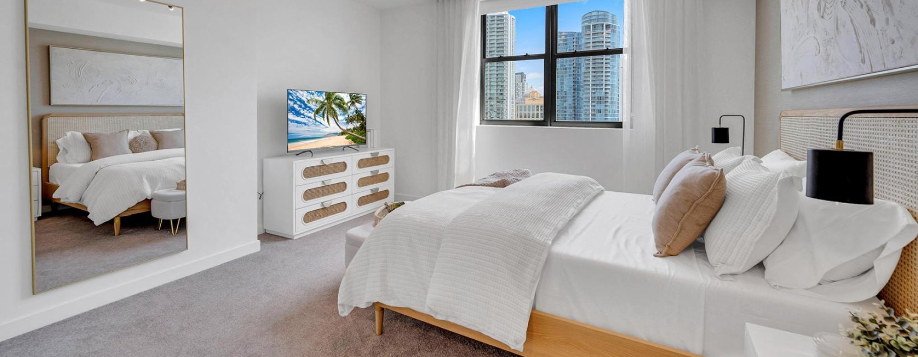 a bedroom with a bed tv dresser chandelier window and mirror